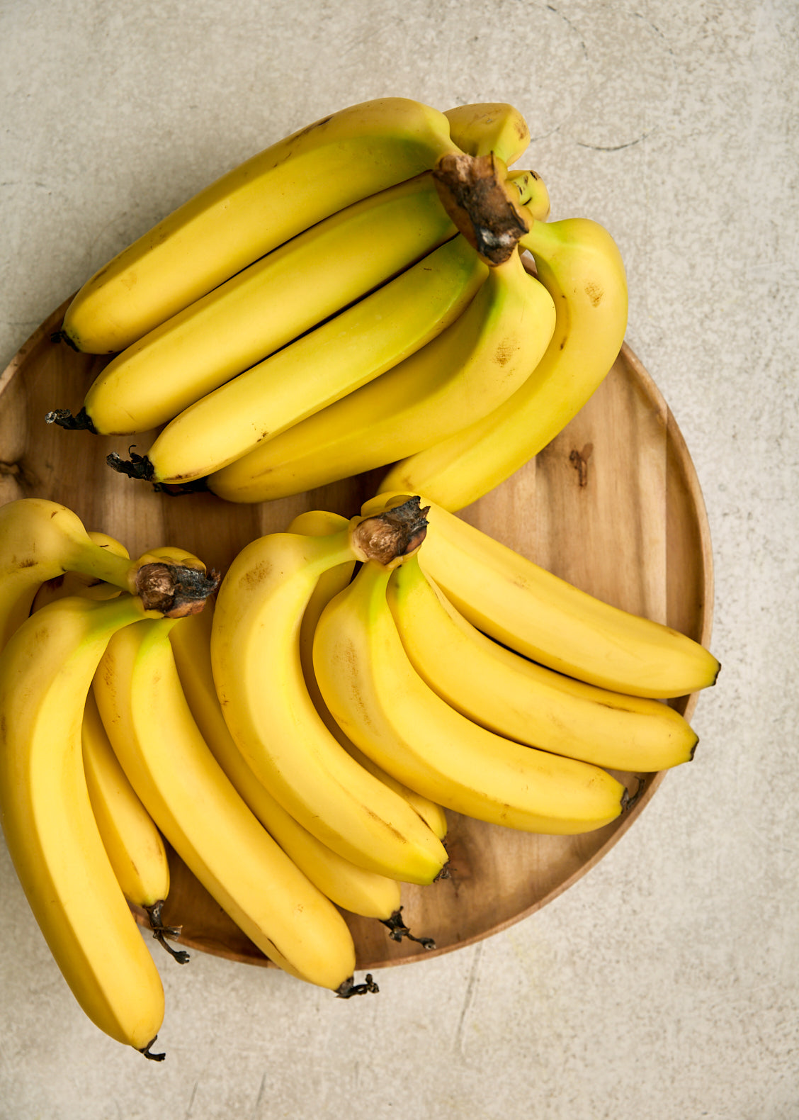 3 bunches of yellow bananas on a wooden platter