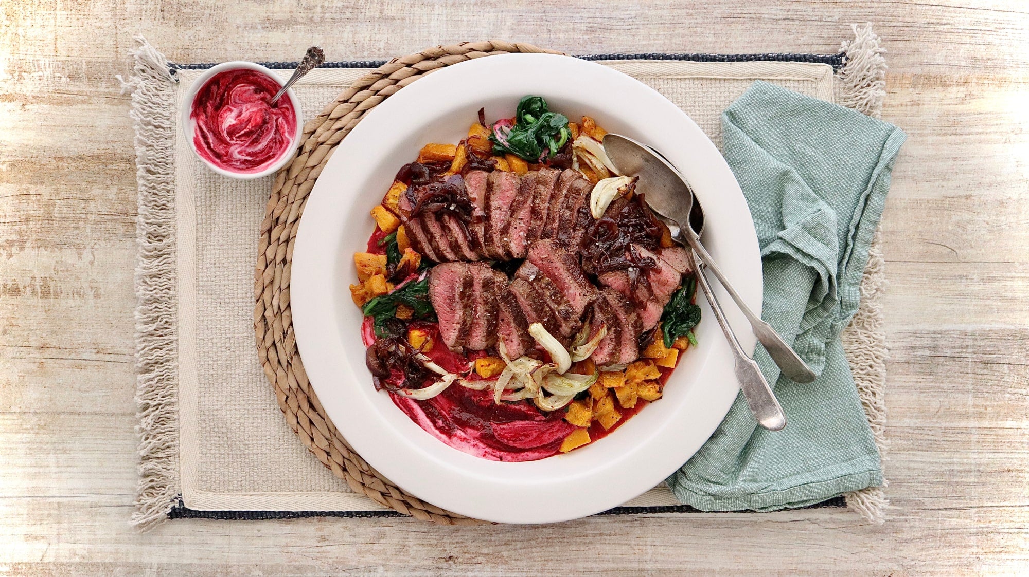 A picture containing a plate of cooked and sliced lamb backstrap with beetroot yoghurt and roast pumpkin and fennel.