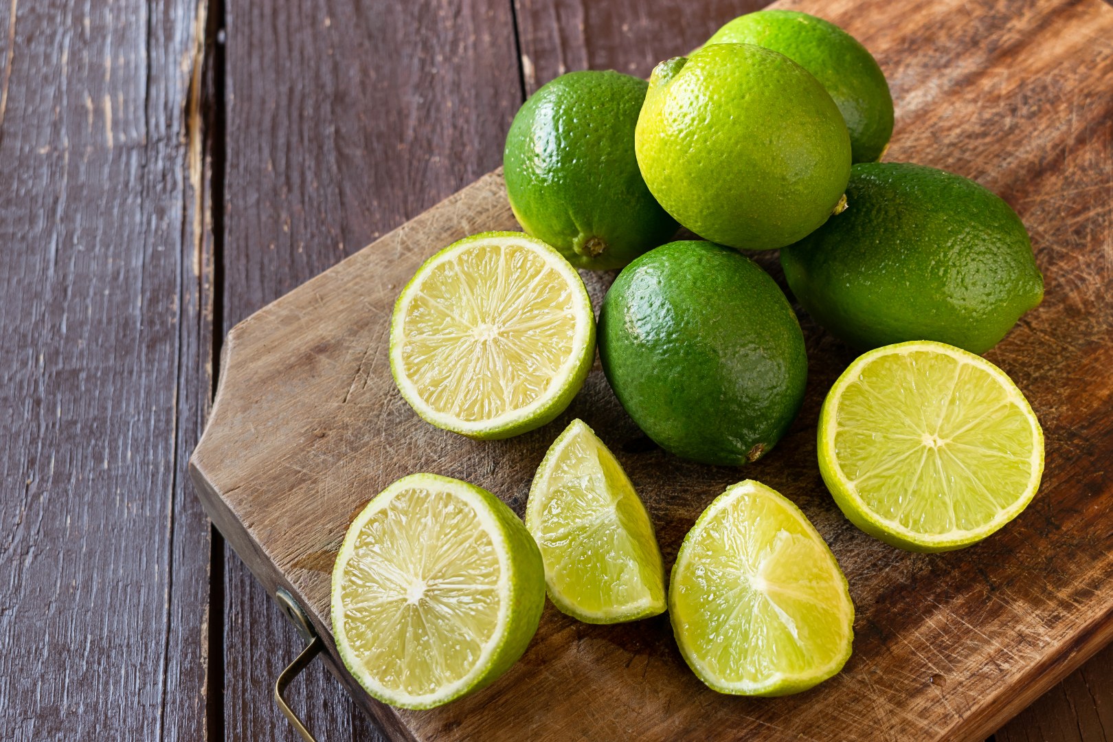 Juicy Tahitian limes grown in Queensland, presented on a chopping board - some halved some whole