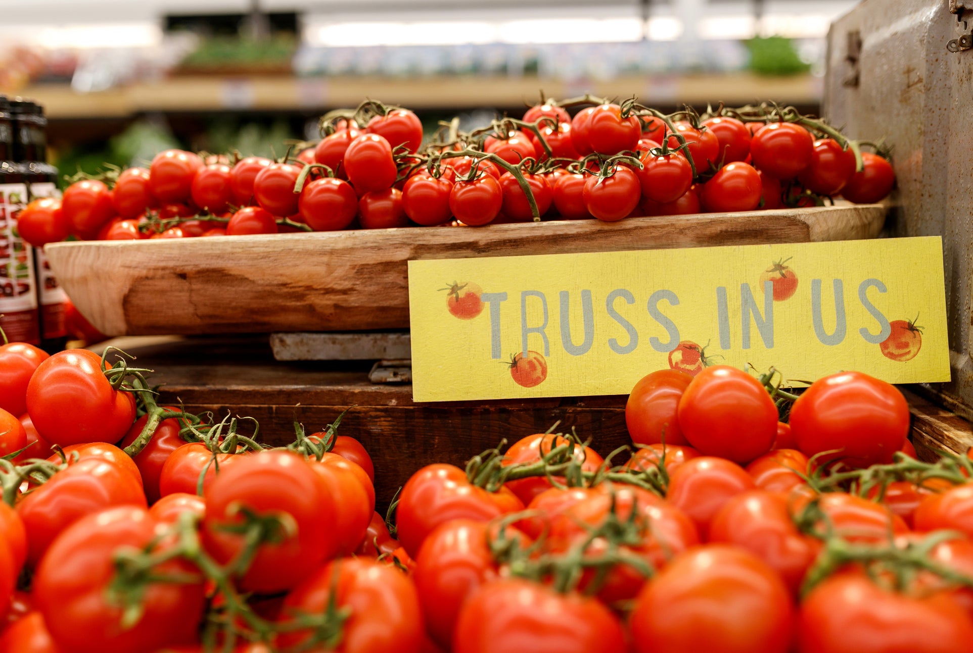 Truss tomatoes on a market shelf with a sign that says Truss In Us