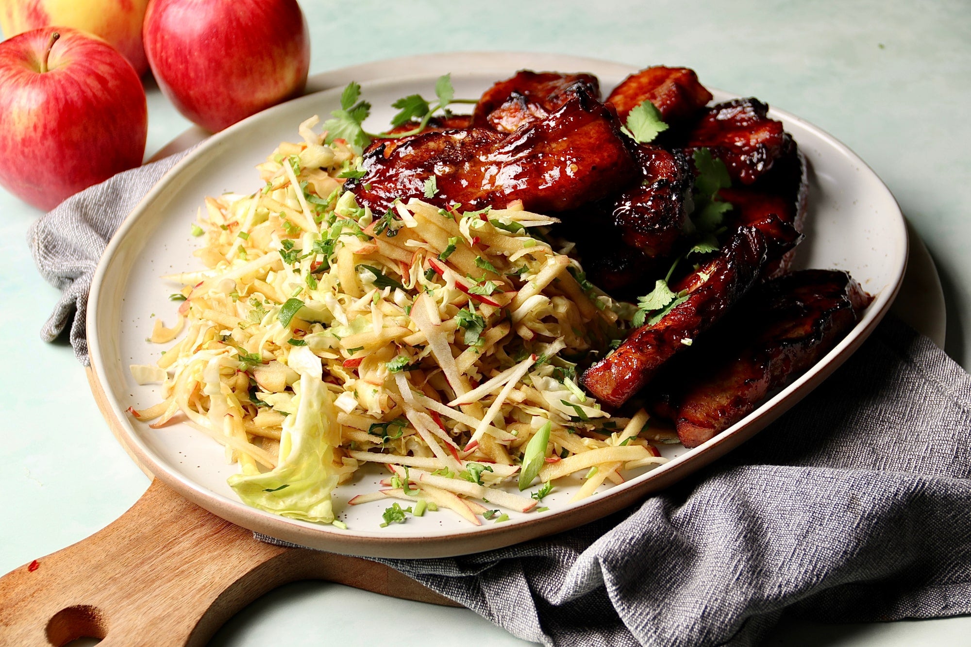Plate of food containing pan fried, marinated pork belly and an apple slaw.