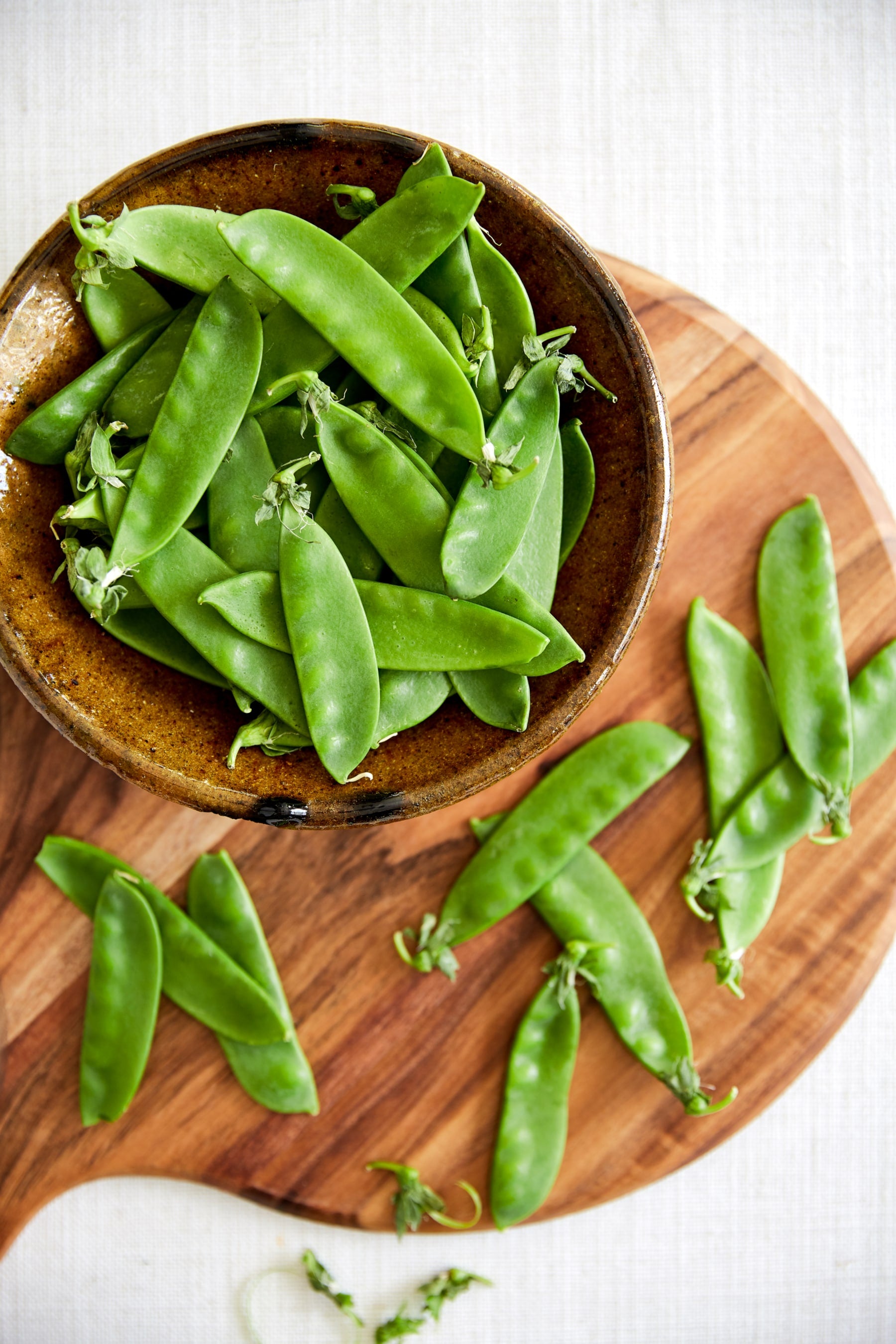 Snow peas in a bowl and scattered on a serving platter