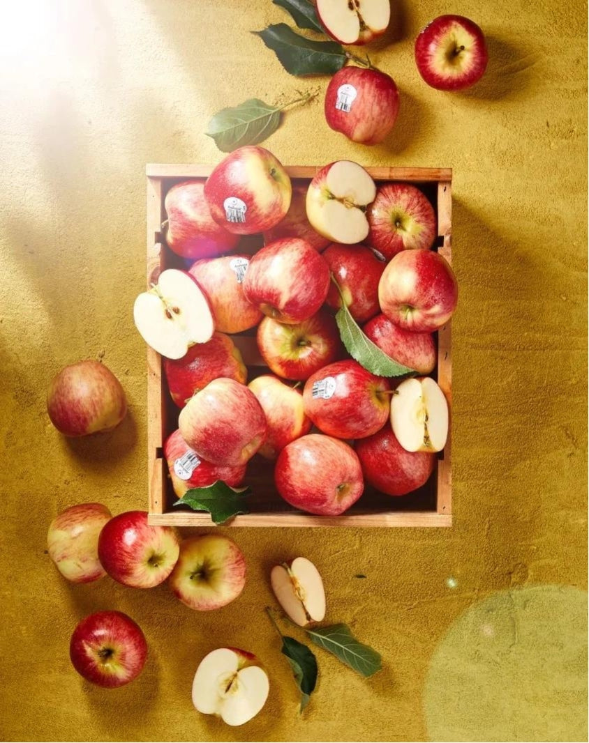 Crate of Ambrosia apples.  Some are whole and some are cut.  It overflows to the top and bottom of the image.