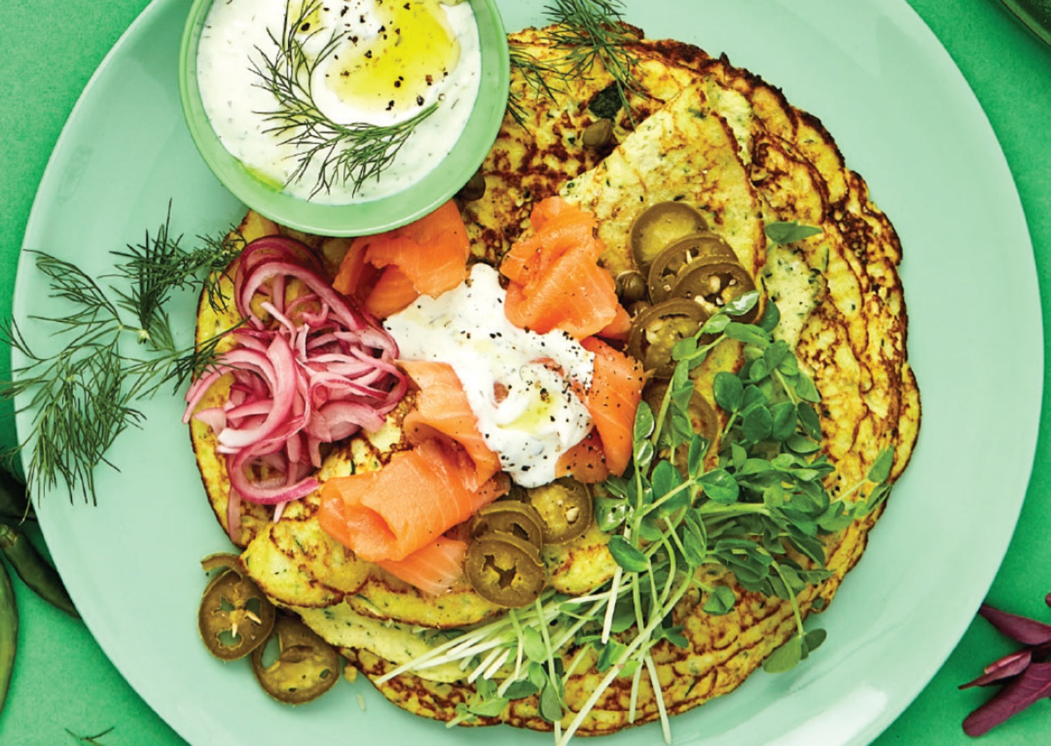 A plate of zucchini crepes topped with smoked salmon, red onion and dill