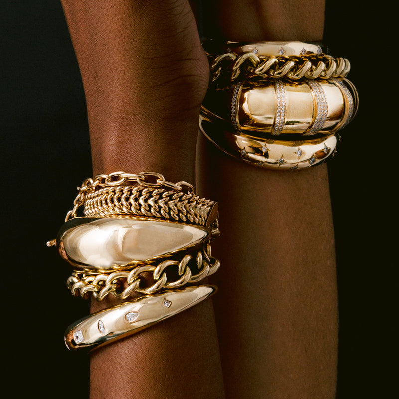 a close up of a woman's wrists next to each other stacked with Zoë Chicco 14k Gold Large Aura Cuff Bracelet and several other bracelets
