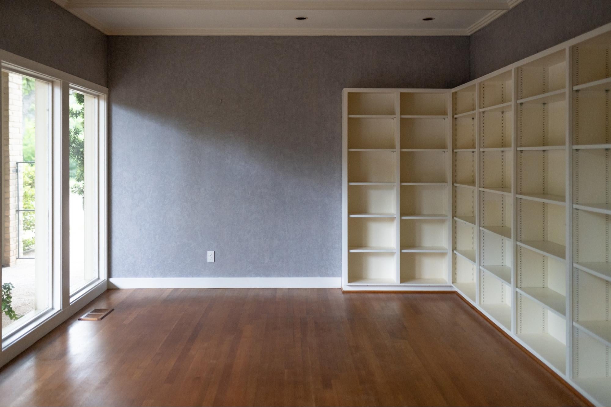 An empty room with grey walls and white shelving.