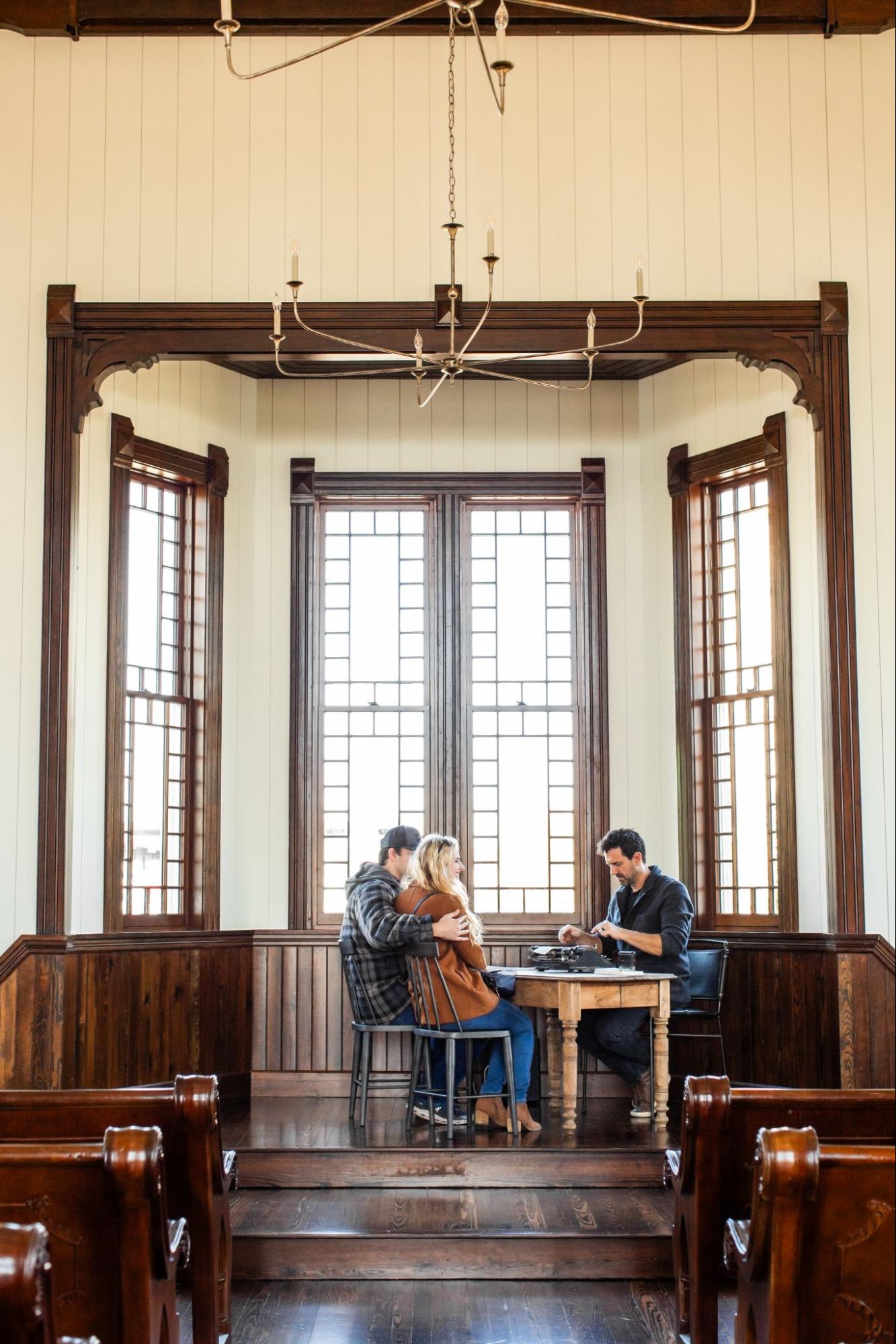 Three people sit inside The Old Church at Magnolia in Waco, Texas.