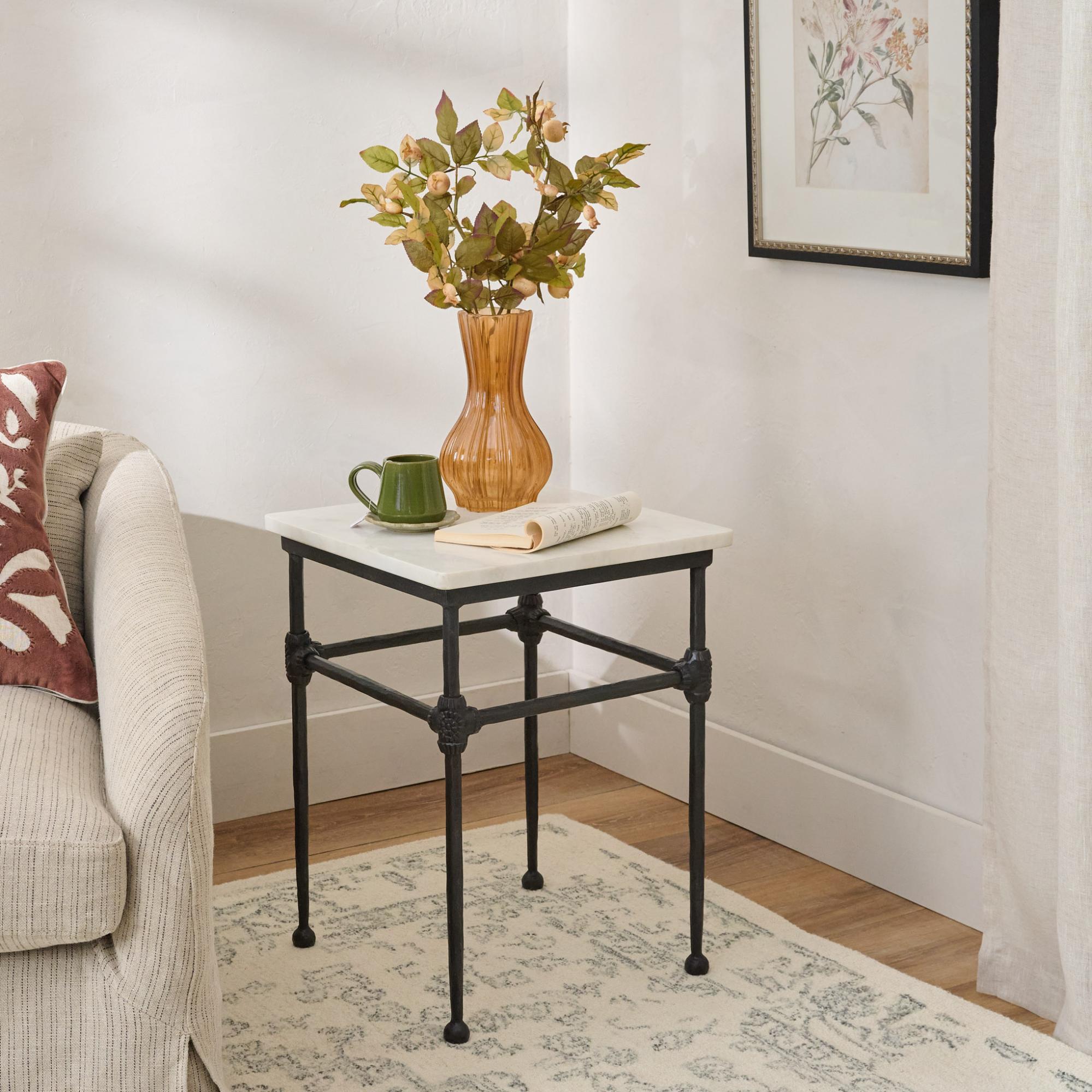 Orange vase with leaf sprays on a square side table with metal base