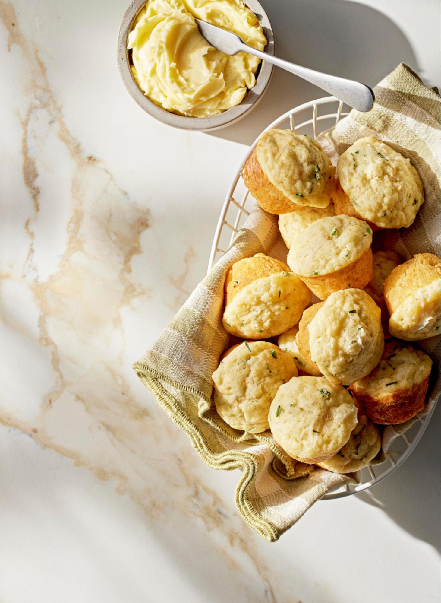 A pile of Parmesan-chive muffins in a white basket. 
