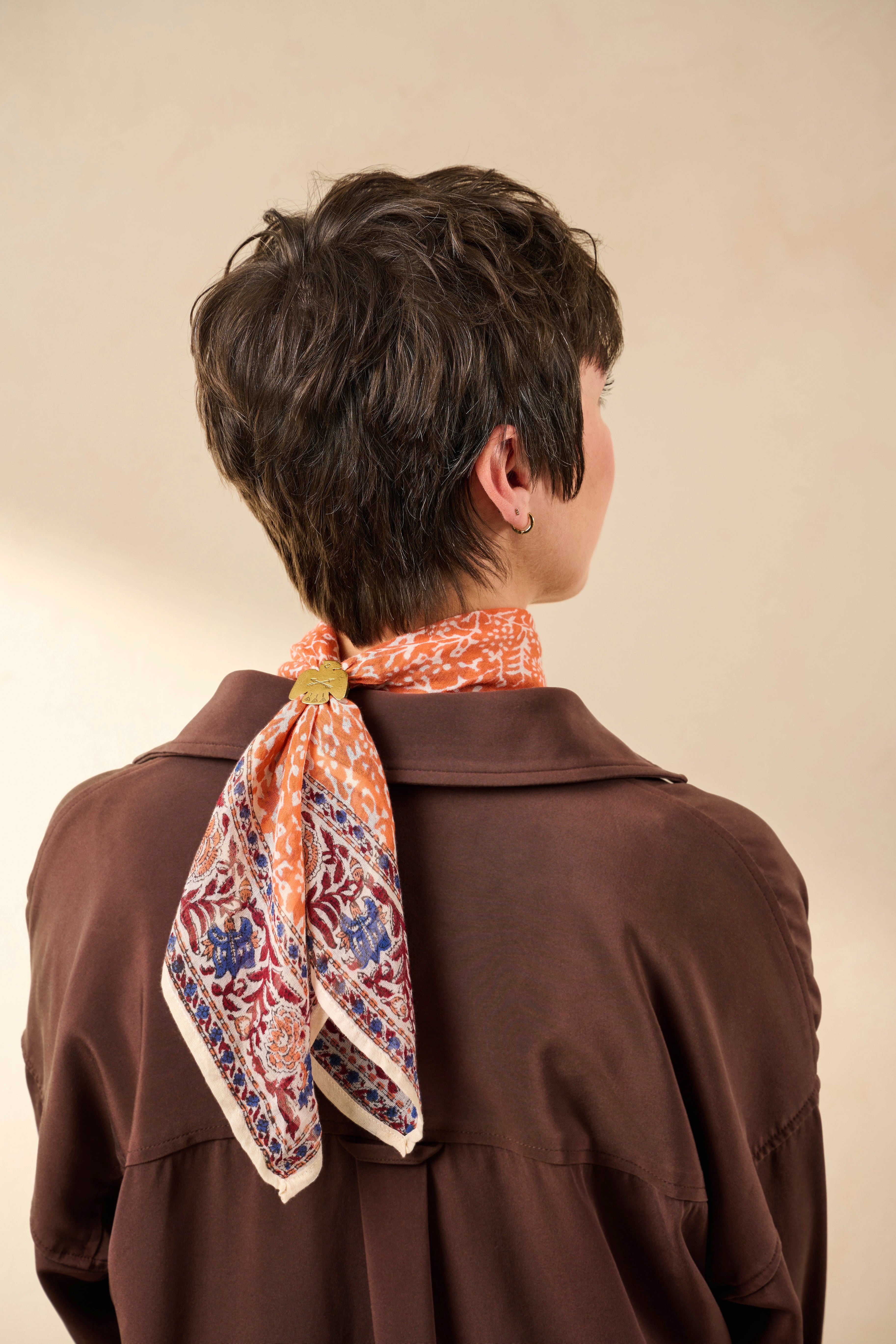 A patterned bandana tied as a neck scarf. 