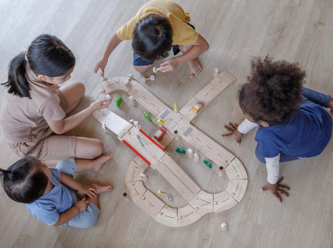 children playing with PlanToys wooden car track