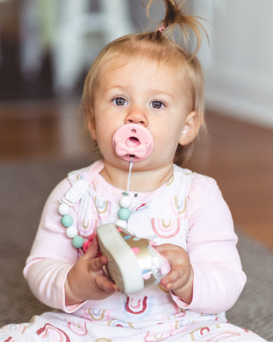Calm and cute toddler with pink pacifier