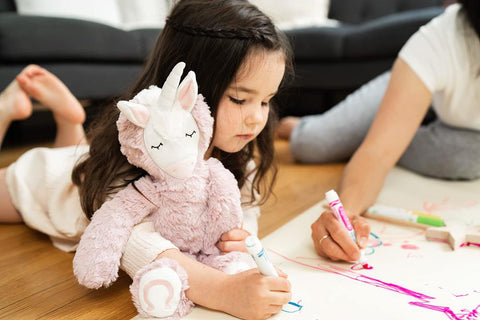 little girl drawing with slumber kins unicorn plushie