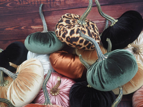 A pile of velvet pumpkins in various colours. Green, cinnamon, pink, gold, black and leopard pring