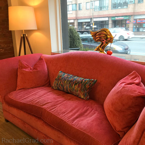 abstract multicolor pillow on pink couch by artist rachael grad