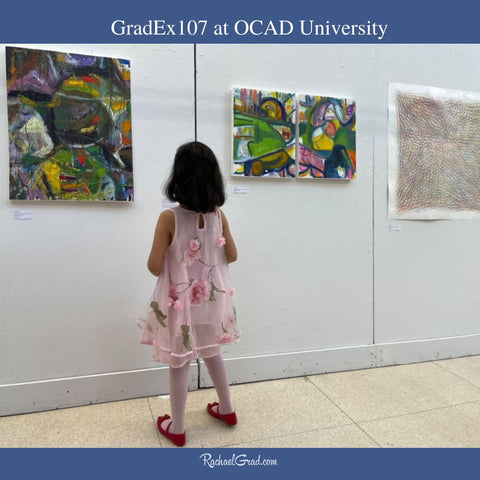 Girl looking at paintings by Rachael Grad at GradEx 107 at OCAD University