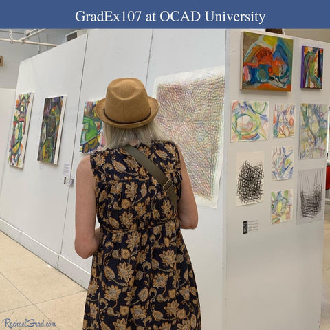 woman looking at paintings by Rachael Grad at GradEx 107 in OCAD University