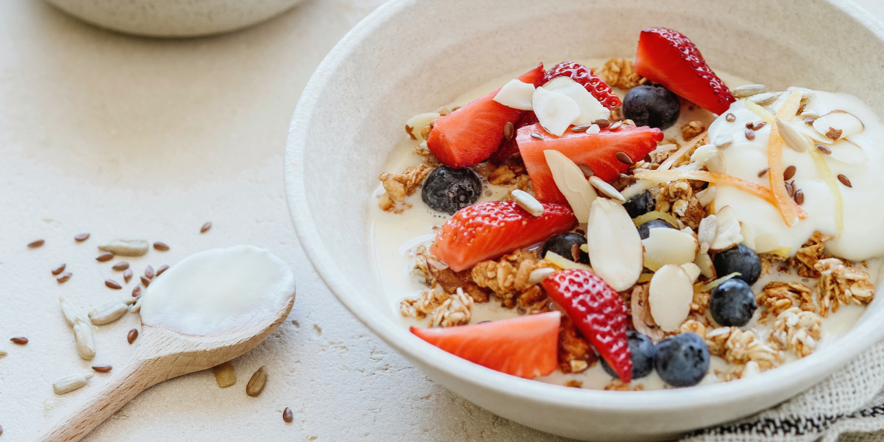 bowl-of-yogurt-topped-with-pieces-of-fruit-seeds-and-almonds