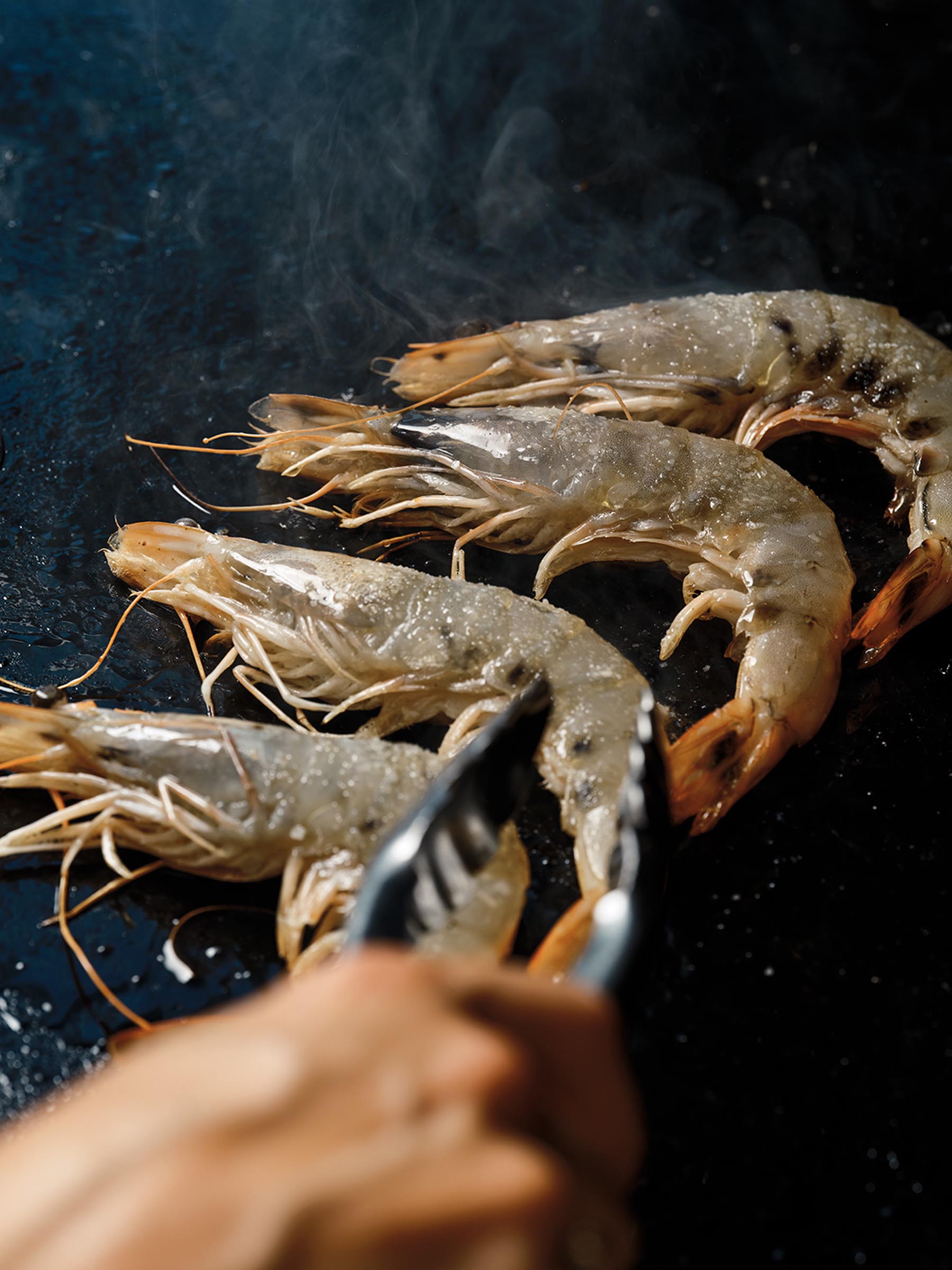 four large seared shrimp on a dark cloth