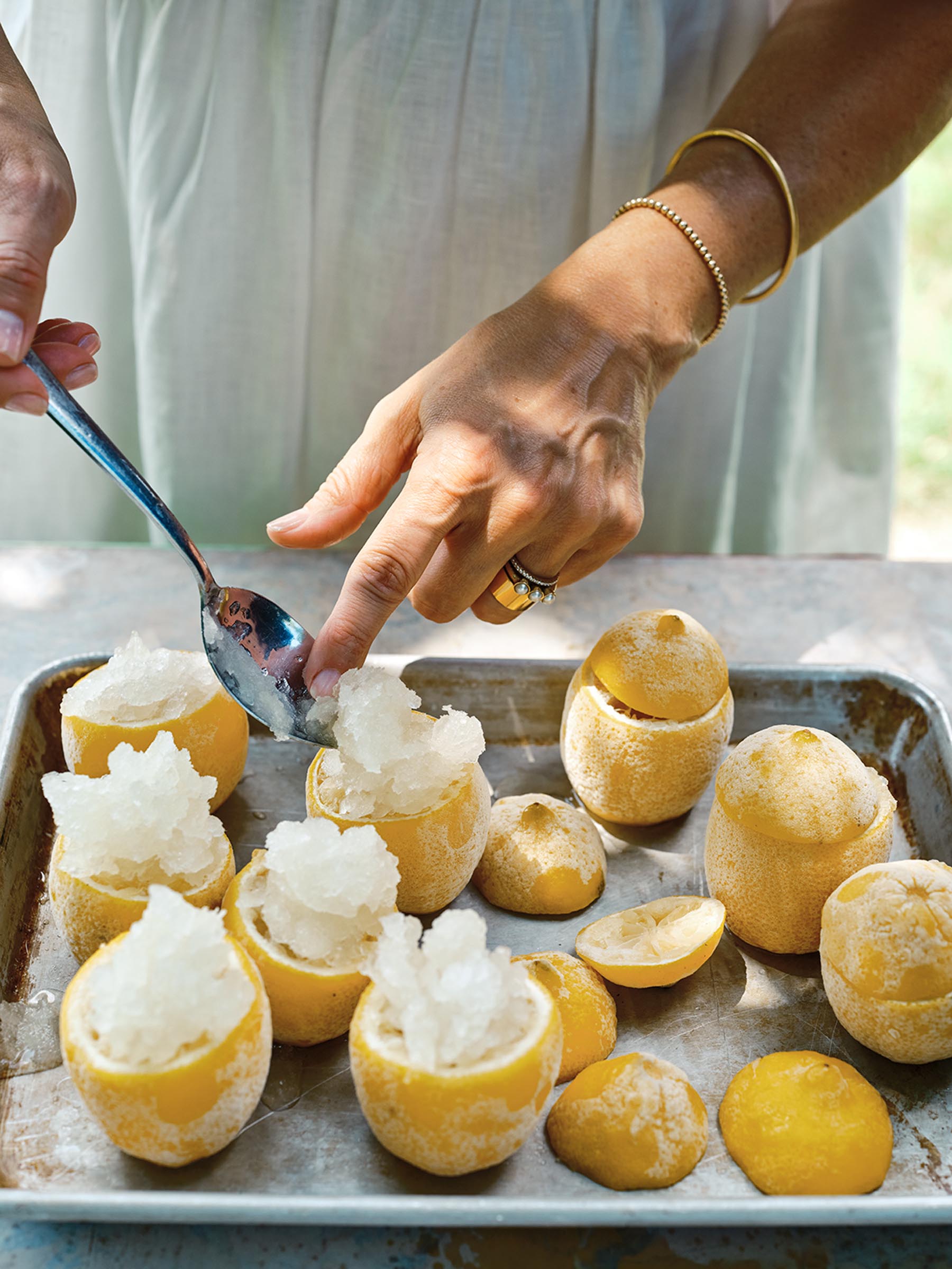 person spooning crushed ice into hollowed out lemons