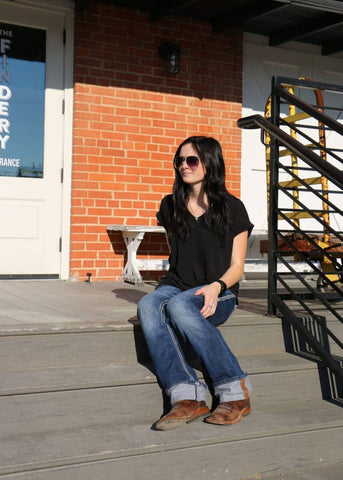Woman sitting outside wearing black shirt and jeans