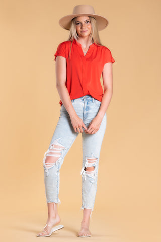 Woman wearing classic top and light blue distressed jeans