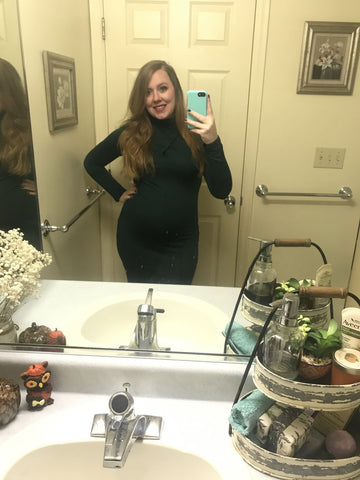 Pregnant woman taking selfie in mirror while wearing dress