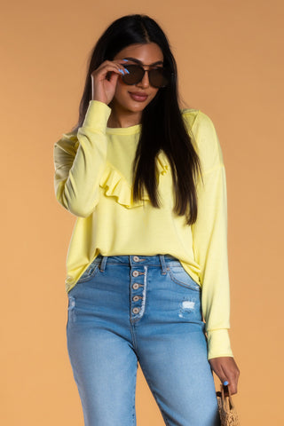 Brunette woman wearing yellow modest sweatshirt, jeans, and sunglasses