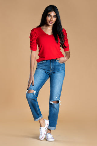 Brunette Girl with Red Ruched Sleeve Top, Jeans, and white tennis shoes.