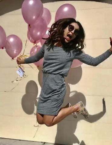 Woman jumping in air holding balloons