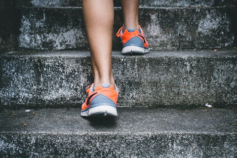 Person wearing orange and gray sneakers walking up stairs