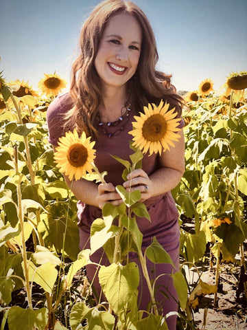 Woman wearing day-to-day pocket dress and standing behind sunflowers