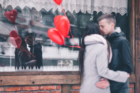 Couple kissing and holding balloons