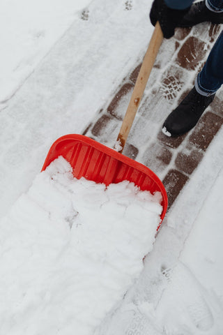 Person removing snow with red shovel