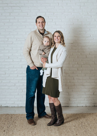 Woman wearing olive relax dress posing with husband and baby
