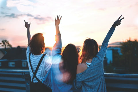 Three women raising arms together