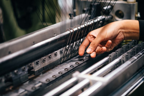 A person working with a clothing loom for slow fashion production