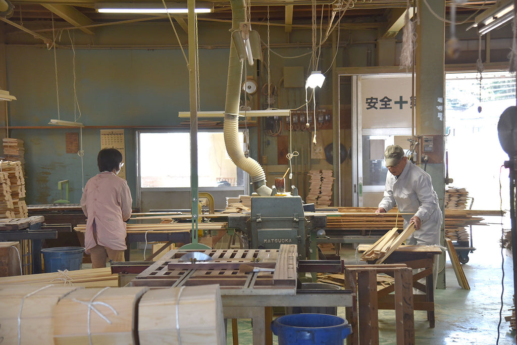 Workers feeding wood pieces into planer