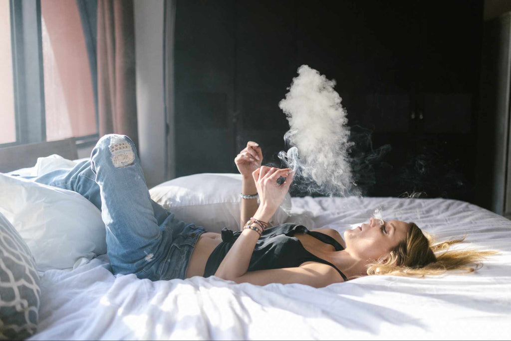 woman lying on bed while smoking