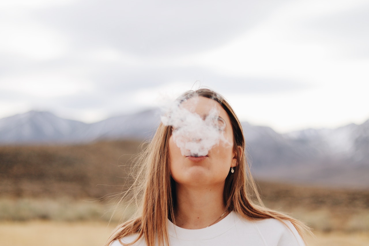 woman blowing smoke outdoors