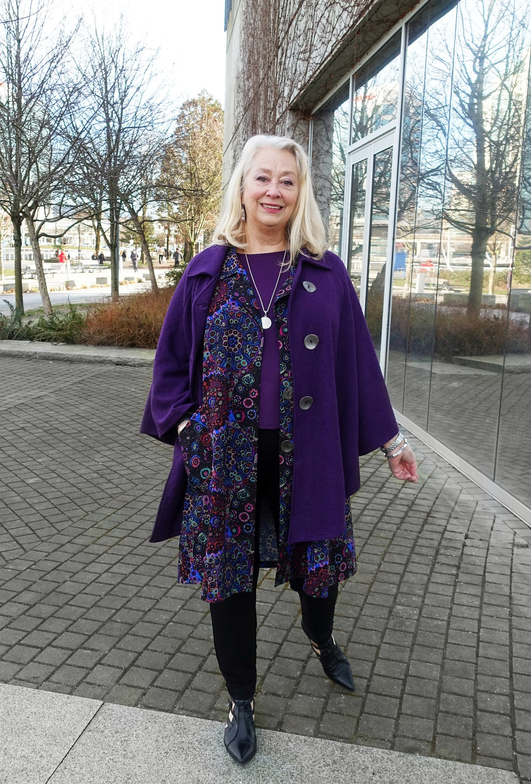 silver haired model wears a purple cape and outfit by designer Diane Kennedy