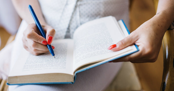 blue pen being held over an open book