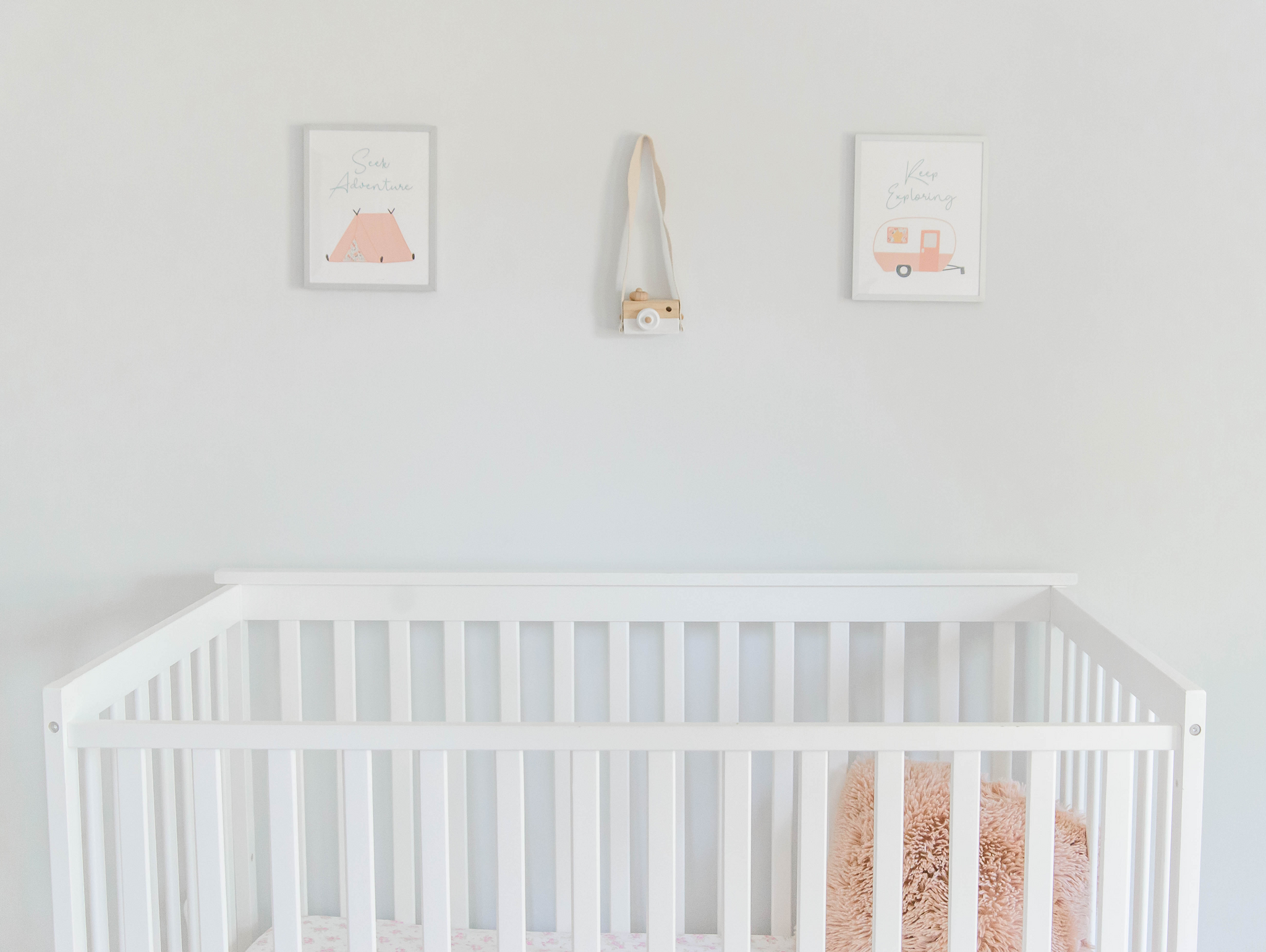 Camping artwork in nursery with white crib