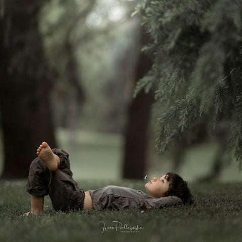 ولد يستلقي على العشب وينظر إلى الغيوم