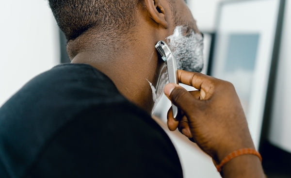 man shaving using beard oil as a pre-shave oil