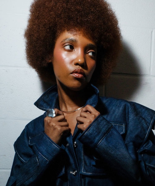 fashion model with afro wearing kabasia denim jumpsuit and delia langan silver jewelry