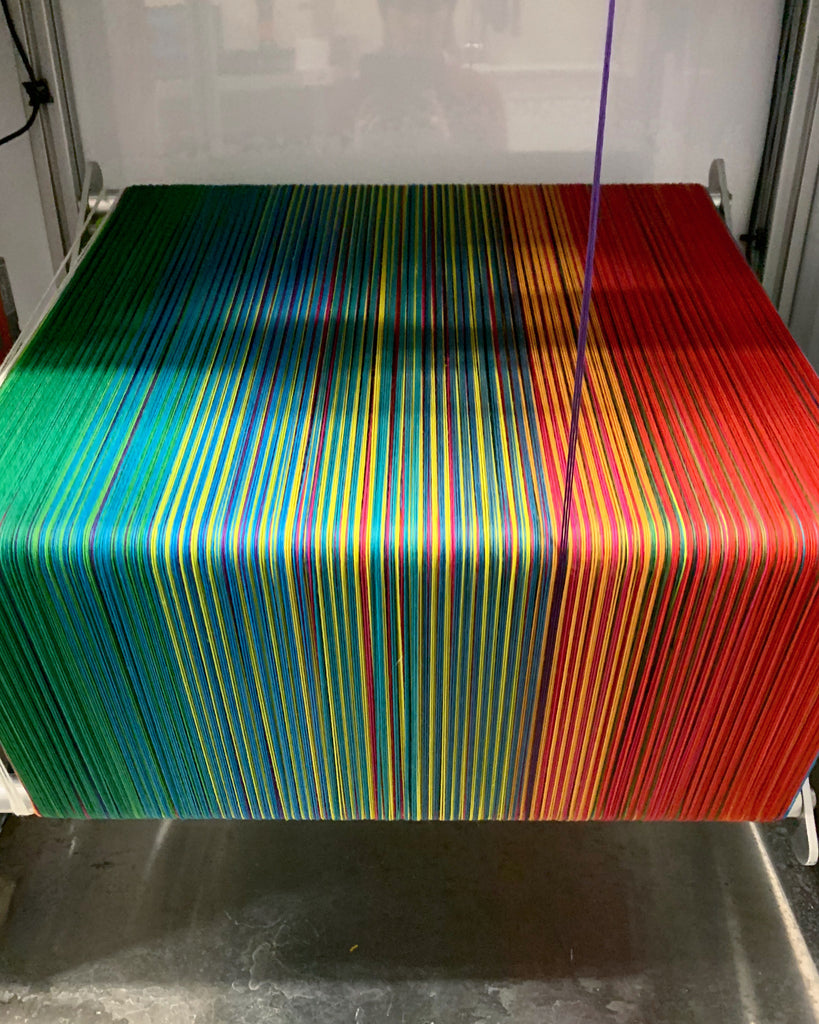 rainbow yarn wound on a large rack 