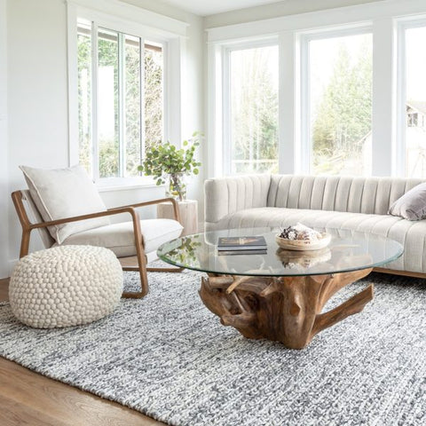Tree root coffee table base with glass top in a white room with white furniture