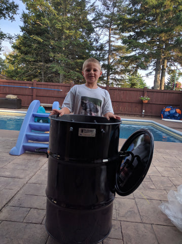 Tristan (10), helps his father Joel light the coals and load up the PBC in New-Brunswick, Canada