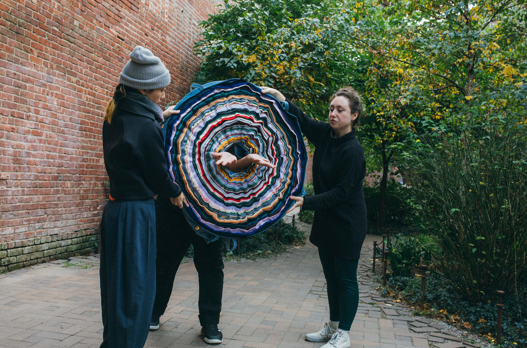 Two people holding up a multi layered fabric circle.